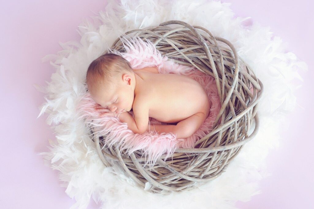 Schlafendes Baby in einem Nest mit Federn umgeben
