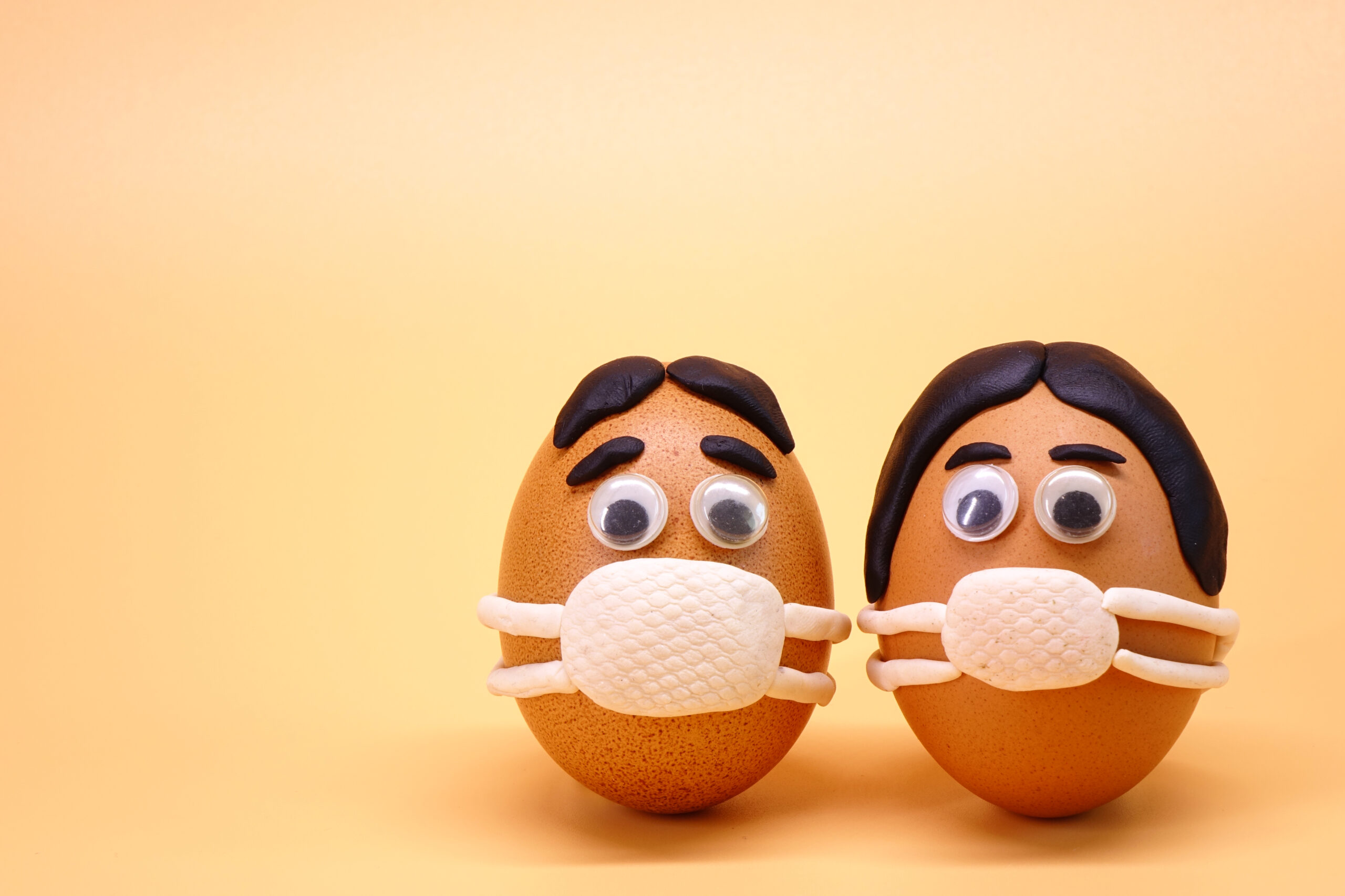 Zwei Eierköpfe mit Masken als Symbol für das Virus